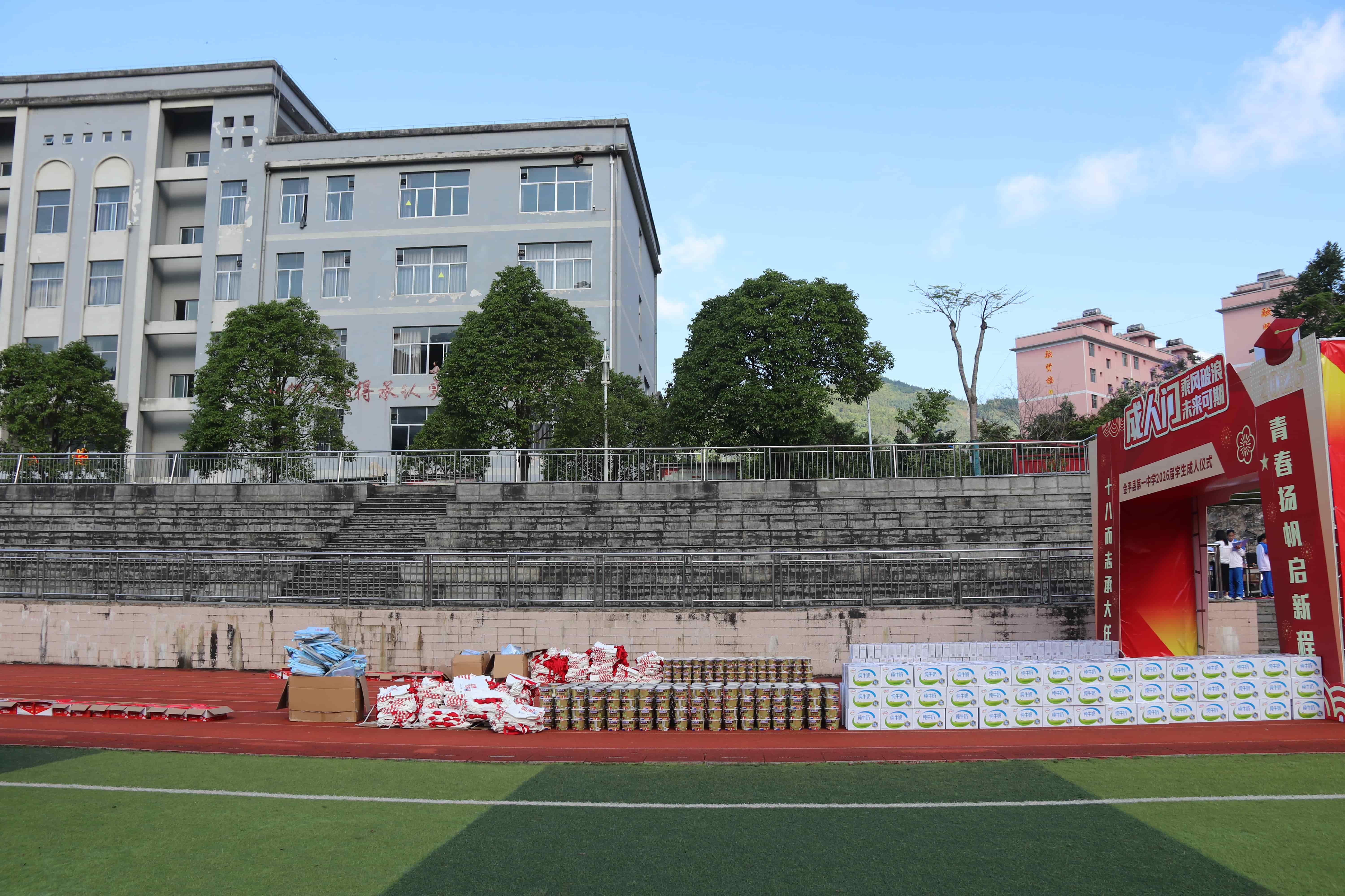 Wide view of the ceremony venue with supplies and school building